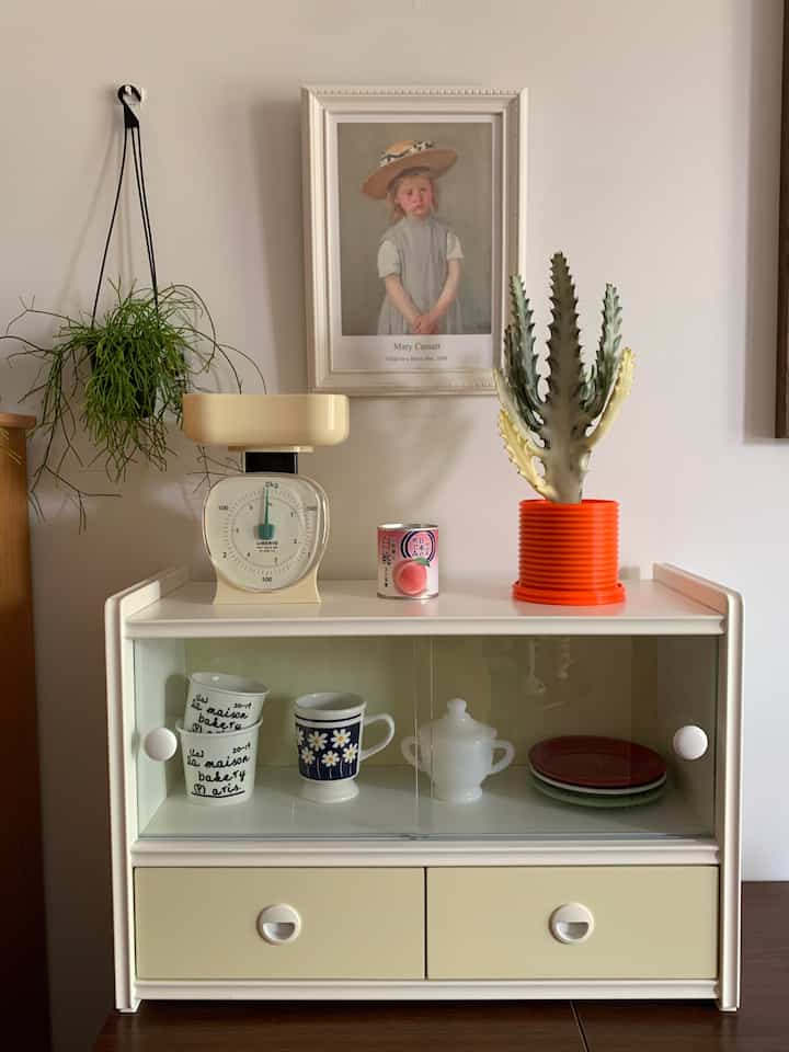 アイボリー調のキッチンスペース、ヴィンテージのキッチンスケールと食器が配置された雰囲気のあるおうちカフェスタイルのインテリア