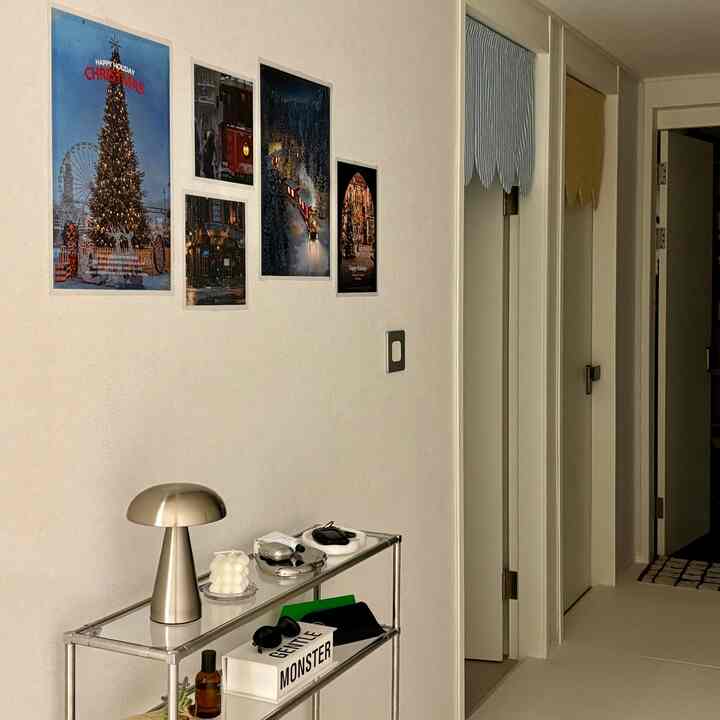 白とシルバー調の廊下空間、クロームのマッシュルームランプと冬のクリスマスポスターが配置されたミニマルなインテリア