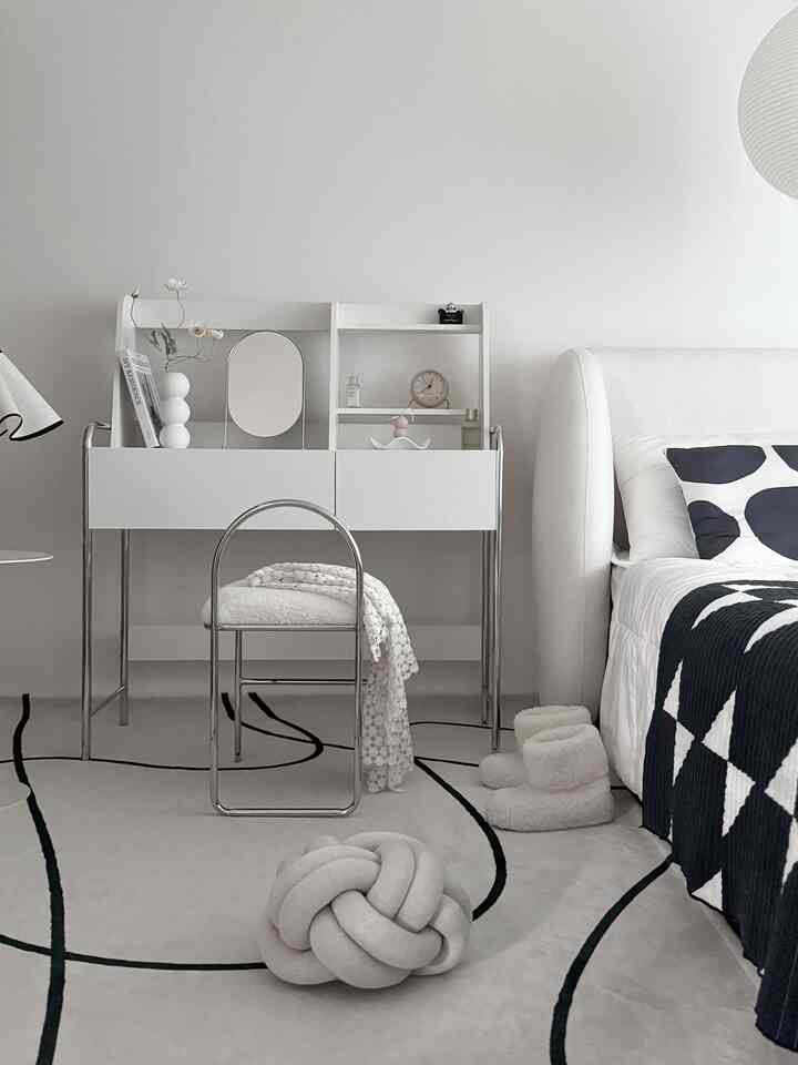 ホワイトとシルバーを基調とした寝室、シンプルなミッドセンチュリーモダンの化粧台とベッドが配置された落ち着いた雰囲気のインテリア