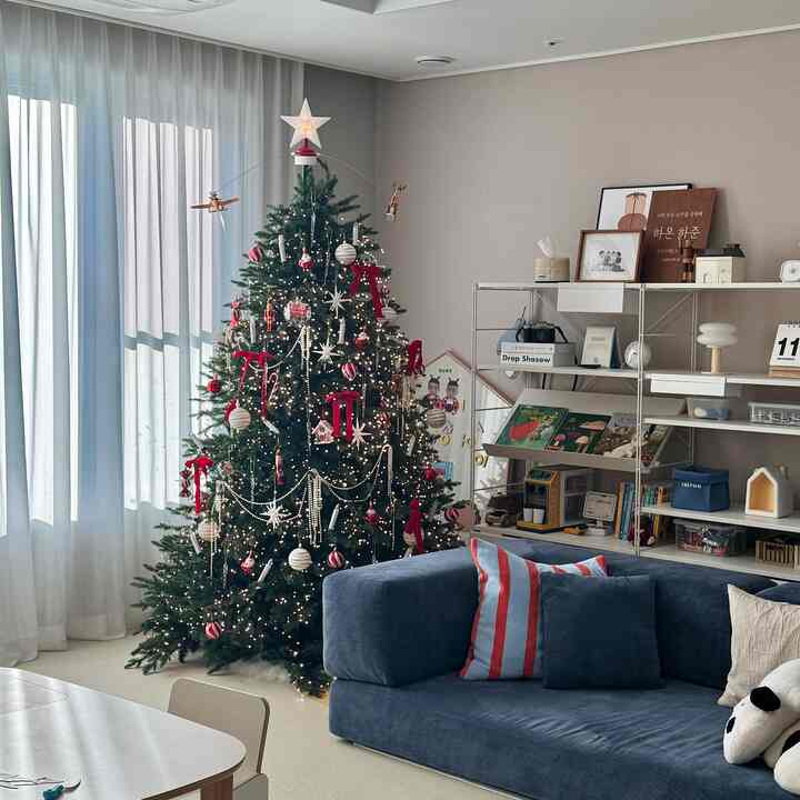 ネイビーカラーのソファと赤い装飾が印象的なクリスマスツリーが配置された子供と暮らすリビング