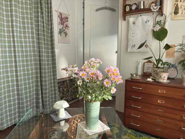 ナチュラルトーンのリビング、花と植物が置かれたガラスのテーブルと木製家具が調和する雰囲気のあるインテリア