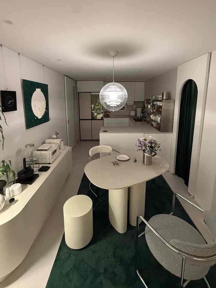 白と濃い緑のトーンでまとめられたモダンで自然な印象のダイニングルーム、丸テーブルと椅子が配置された空間