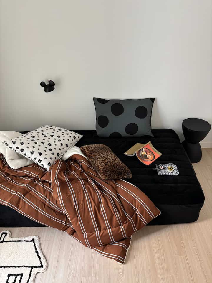 Monotone bedroom featuring a black bed and assorted patterned cushions creating a cozy atmosphere