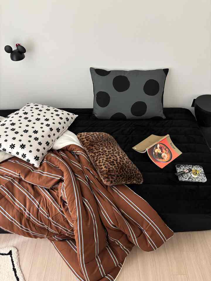 Cozy bedroom in black and brown tones featuring a quilted microfiber mattress cover and polka dot and floral patterned pillows