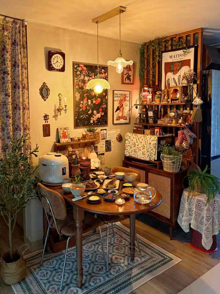 暖かい木目調のヴィンテージキッチン、ダイニングテーブルに料理と植物が配置された雰囲気のある空間