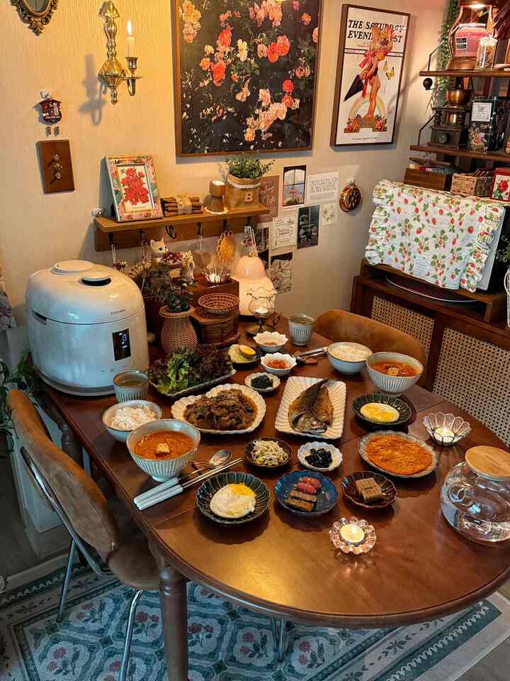 暖かみのあるブラウン調のダイニングルーム、木製のテーブルと椅子に並べられた韓国料理が印象的な雰囲気のあるインテリア