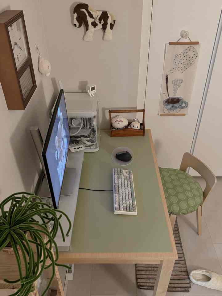 白と淡い緑のトーンの小さなホームオフィス、木製の机と椅子、コンピューターモニターが配置された清潔感ある作業空間