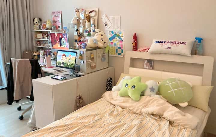 白を基調とした寝室、かわいいオタクグッズとコンピューターデスクが配置された雰囲気のある空間