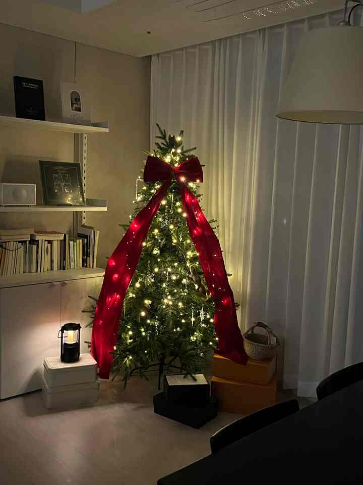 暖かいホワイトとグリーン、レッドの色調のリビング、飾られたクリスマスツリーと照明、カーテンが印象的な雰囲気のあるインテリア