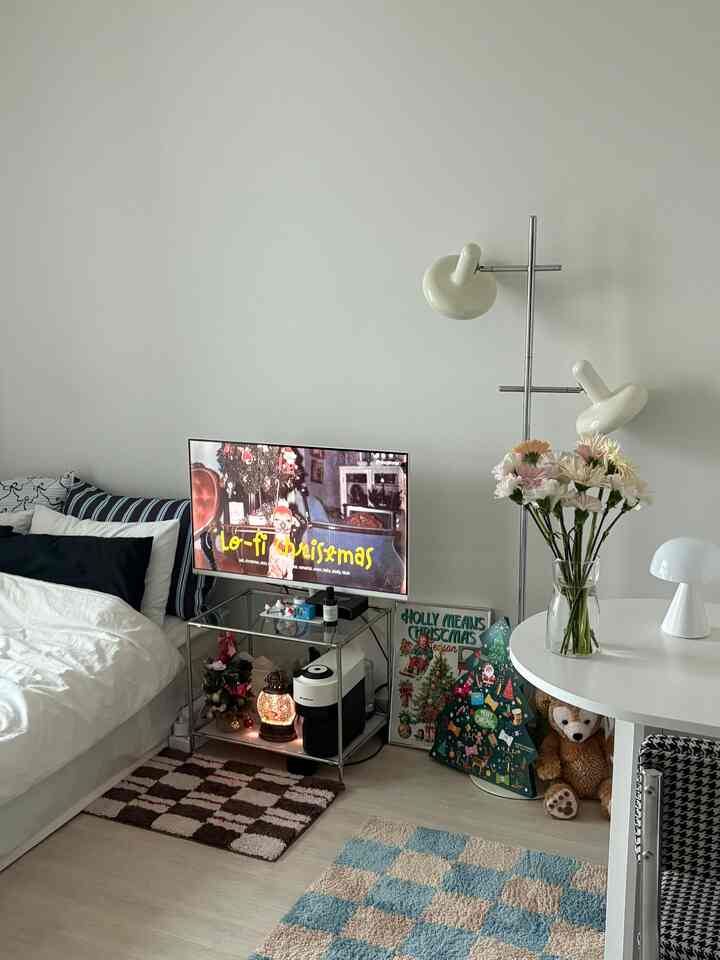 白い壁と木目調の床のワンルームリビング、クリスマスの装飾とダイニングテーブル、テレビ台が配置された雰囲気のある空間