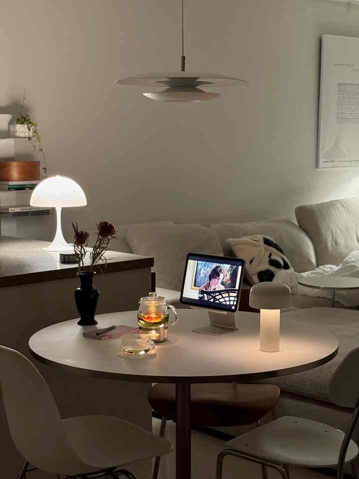 暖かな照明とモダンな円形ダイニングテーブル、ソファが配置された居心地の良いリビングルーム