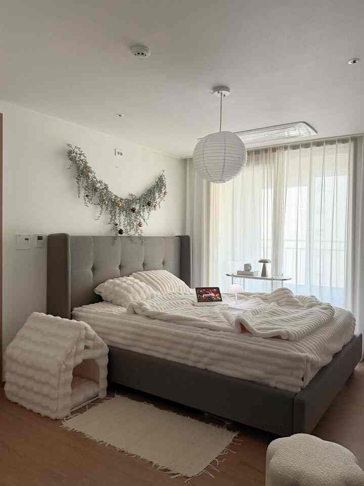 白とグレーのトーンの寝室、グレーのベッドフレームと白い寝具が配置された雰囲気のある空間