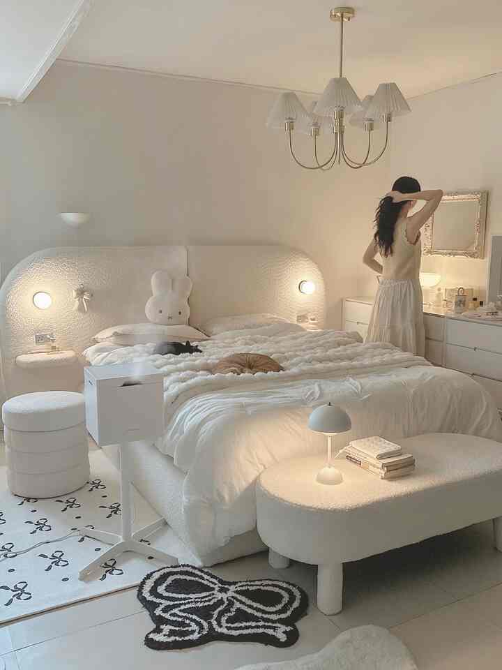 白を基調とした寝室、柔らかな曲線のベッドとスツール、二匹の猫が寝そべる温かみのあるインテリア