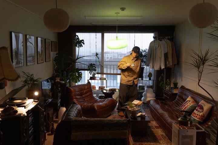 温かみのあるブラウンのレザーソファと植物が調和したナチュラルでレトロな雰囲気のある居心地の良いリビングルーム