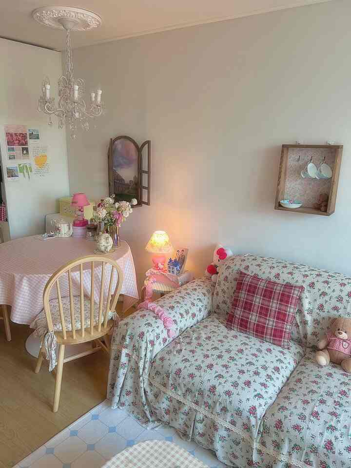 ホワイトとピンクのトーンのリビングルーム、フレンチカントリースタイルの花柄ソファと木製ダイニングテーブルが配置された雰囲気のあるインテリア