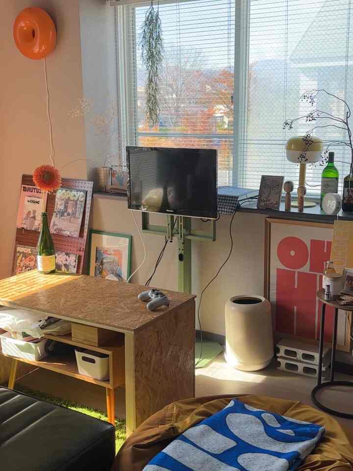 温かみのあるナチュラルな色調の小さなリビングルーム、木製のコーヒーテーブルとテレビ、ビーンバッグとソファが配置されたモダンなインテリア