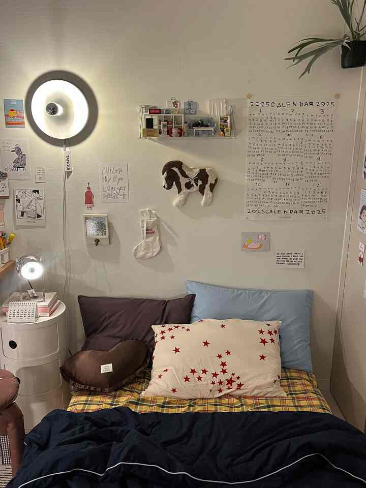 柔らかい色調の小さな寝室、ベッドと枕、造り付けのクローゼット、壁の照明、壁飾りが調和した雰囲気のあるインテリア