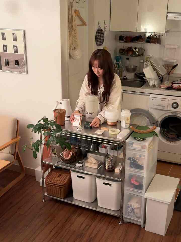 白とナチュラルな色調のコンパクトなキッチンスペース、ステンレス棚と整理された収納がある実用的なインテリア