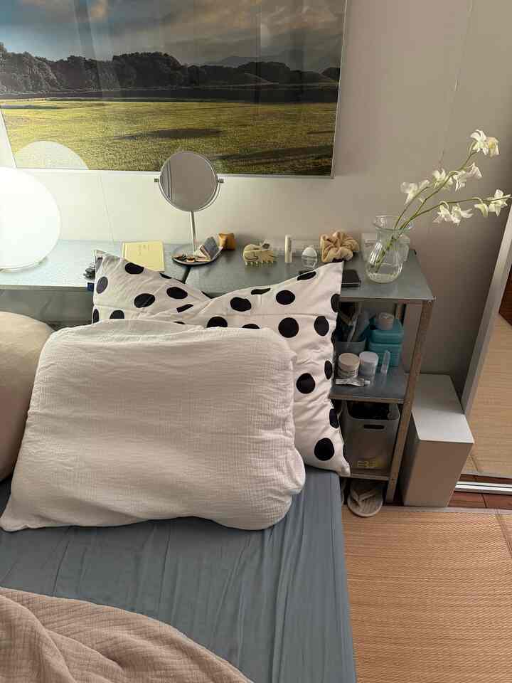 ホワイトとグレーの色調の寝室、枕と金属棚が配置された落ち着いた雰囲気の空間