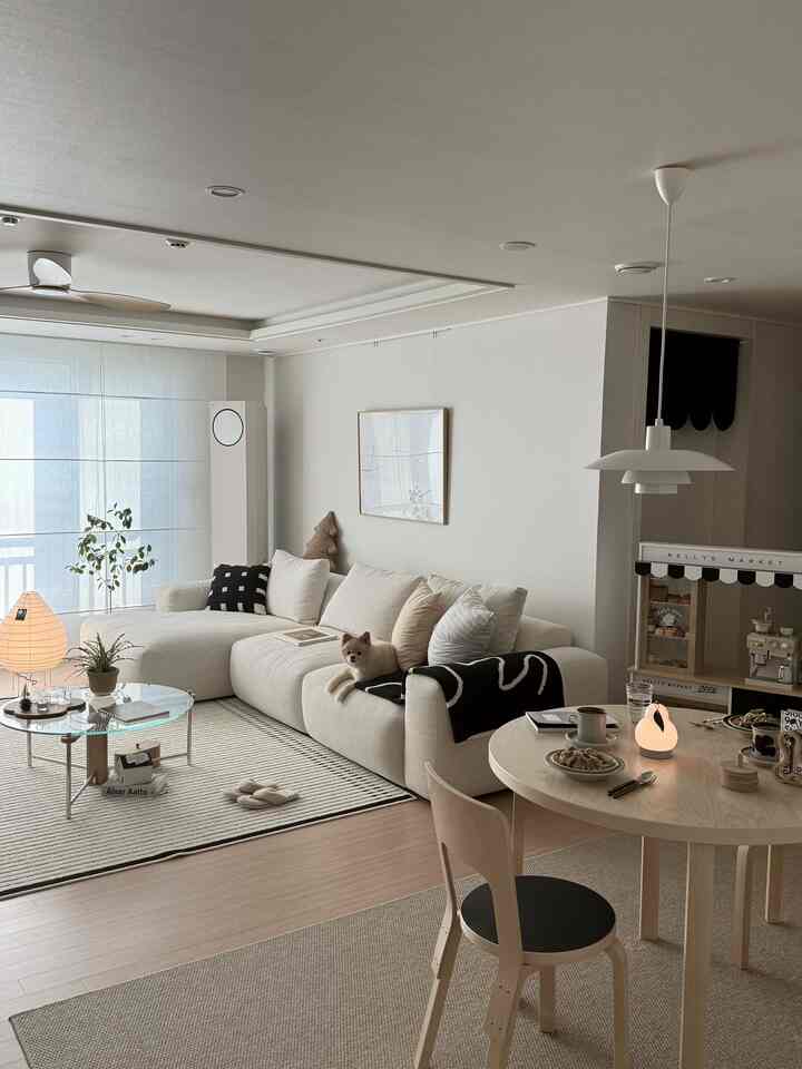 明るいナチュラルな色調のリビング、ベージュのファブリックソファとラグ、木製のダイニングテーブルが温かみのある雰囲気を演出するインテリア