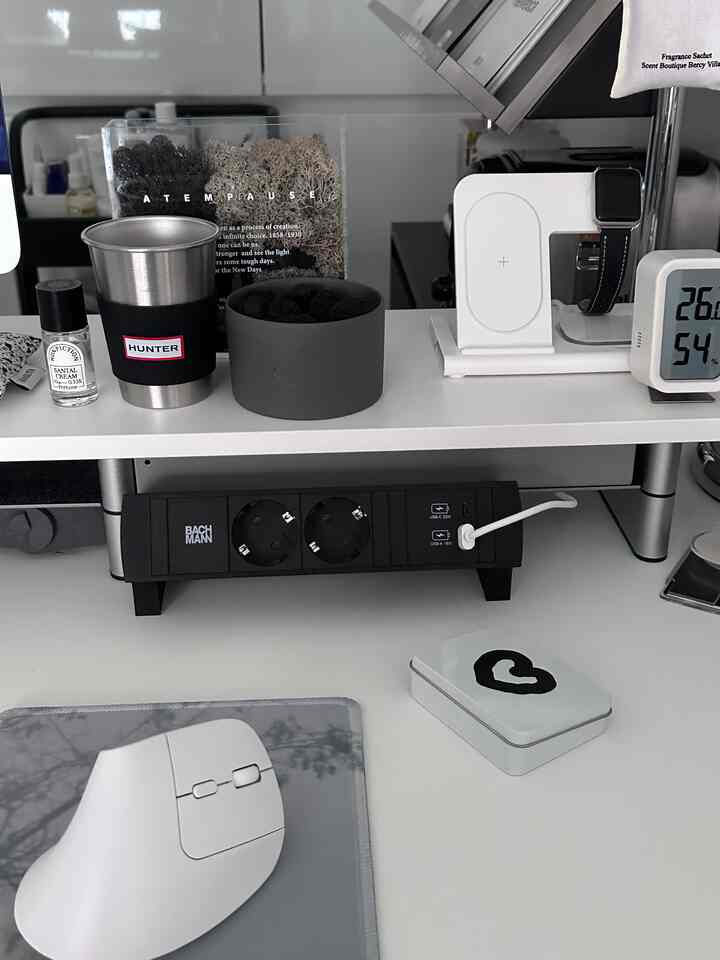 White and black toned home office desk featuring wireless charger and vertical mouse in a clean, organized workspace