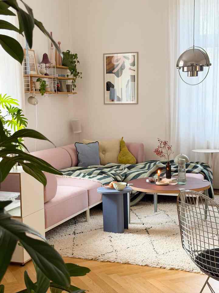 Warm ivory and pink toned living room featuring a corner sectional sofa, rug, and cozy stylish atmosphere