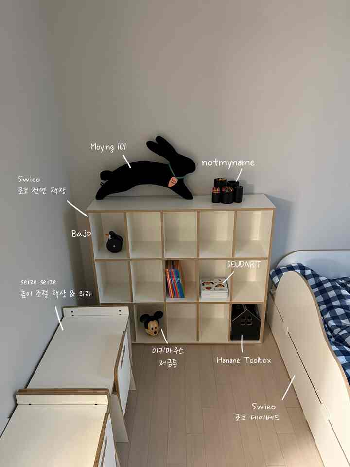 白と木目調の調和が取れた子供部屋、調節可能な机と低いベッド、本棚が整えられたシンプルで雰囲気のあるインテリア