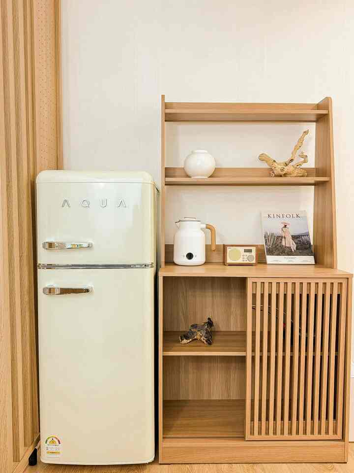 ホワイトと木目調が調和するキッチン空間、レトロスタイルの冷蔵庫とシンプルな木製棚が配置された落ち着いた雰囲気のインテリア