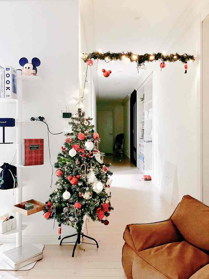 白とナチュラルカラーが調和したリビング、赤い飾り付けのクリスマスツリーとブラウンのビーズクッションソファが温かみのある雰囲気を演出する空間