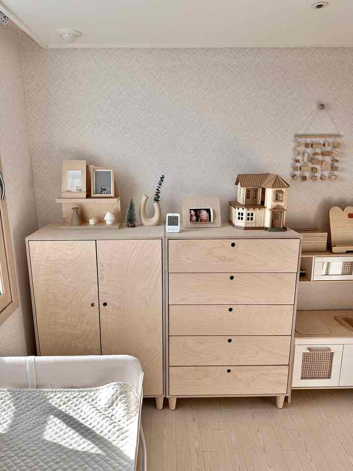 明るい木目調とナチュラルカラーの赤ちゃん部屋、木製家具とベビーベッドが配置された雰囲気のある空間