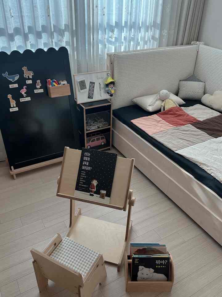 ナチュラルな色調の子供部屋、子供用机とベッド、白いカーテンが配置された雰囲気のあるインテリア