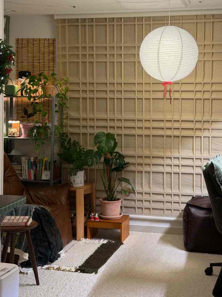 ウッドトーンの壁とブラウンのビーンバッグ、多様な植物が配置された温かみのあるナチュラルなワンルームリビング