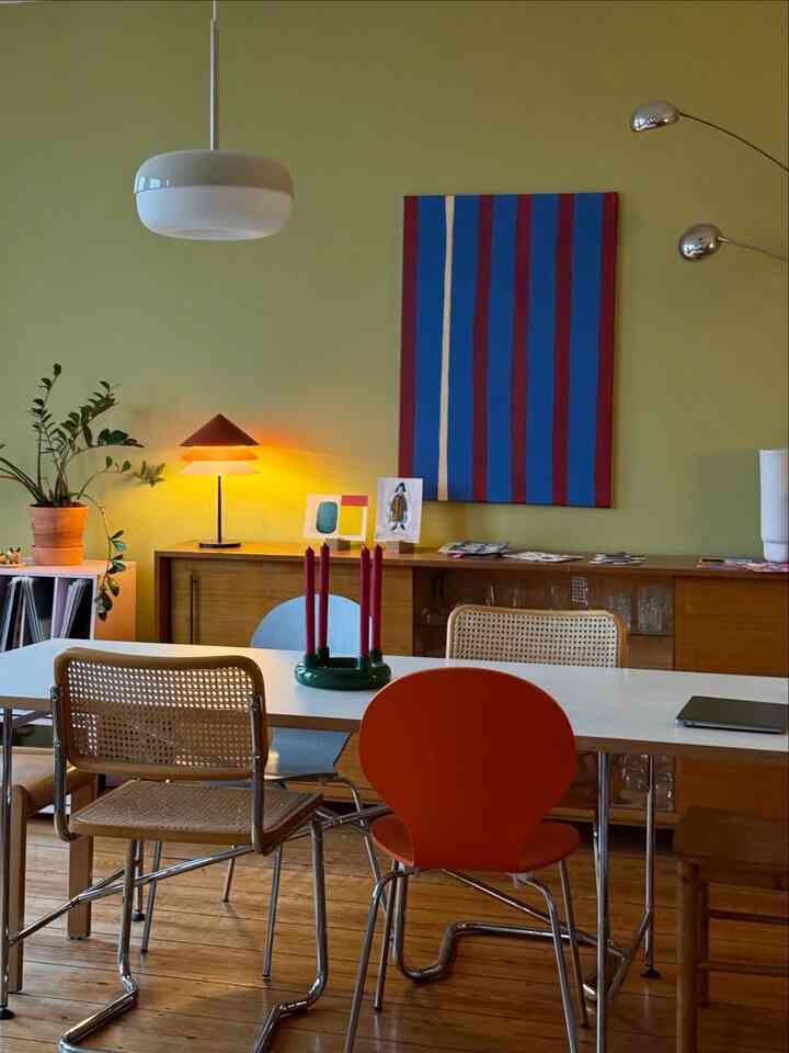 Green-walled dining room with wood tone furniture, featuring pendant light and candles creating a cozy atmosphere