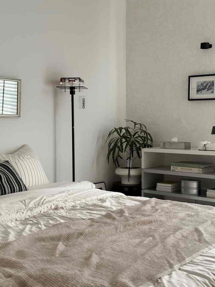 白とナチュラルカラーの寝室、フロアランプと棚、植物が配置された雰囲気のあるヴィンテージスタイルの空間