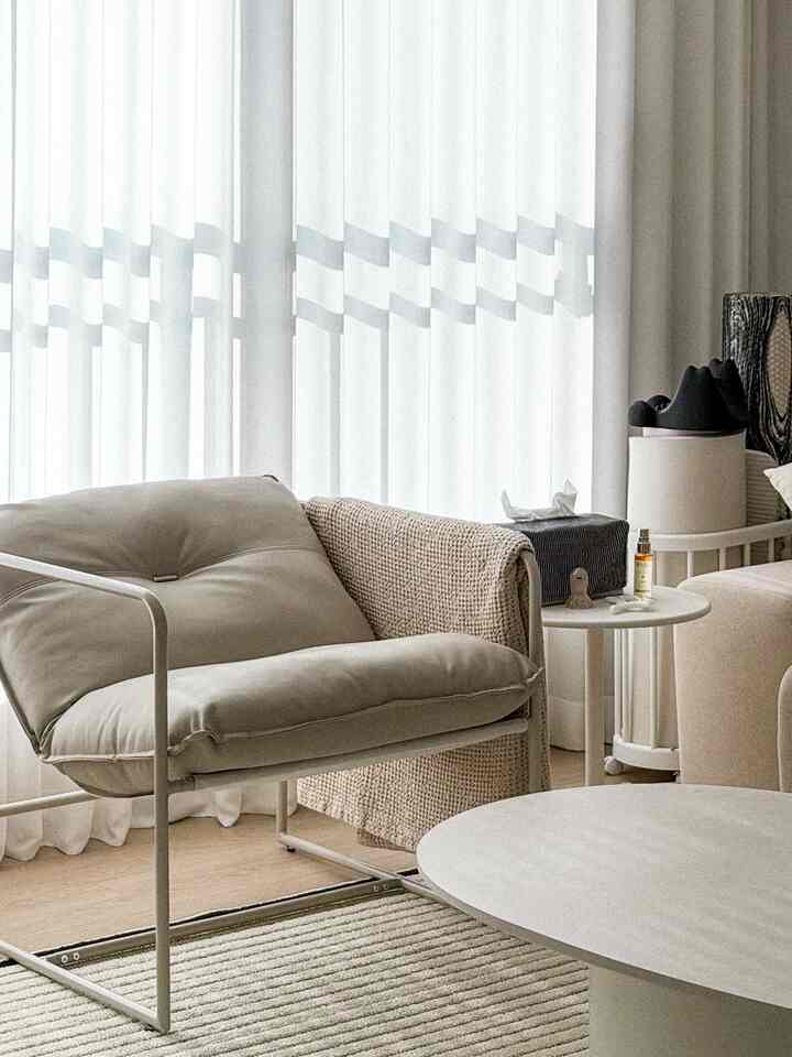 柔らかなベージュとアイボリー色調のリビング、快適な一人用レザーソファとシンプルなコーヒーテーブルが配置された雰囲気ある空間