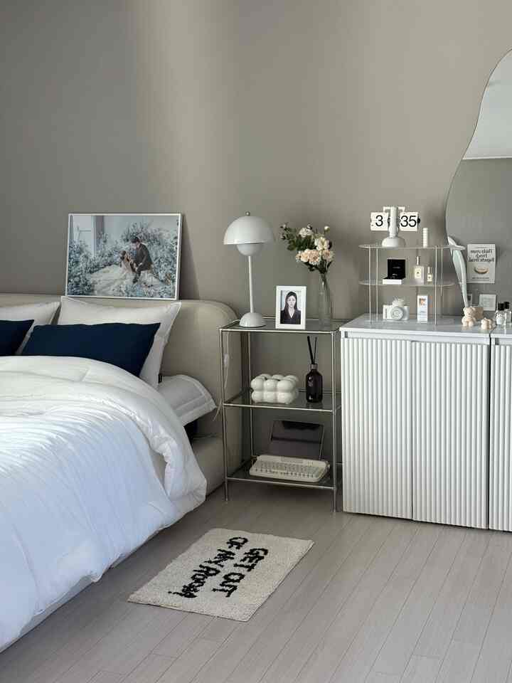 ネイビーカラーのクッションが配置されたホワイトの寝具とベージュの壁が調和するナチュラルモダンな寝室