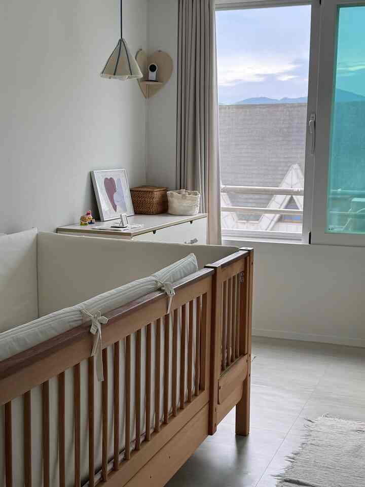 温かみのある木目調と白を基調とした子供部屋、窓とポスター、チェストが配置された居心地の良い空間