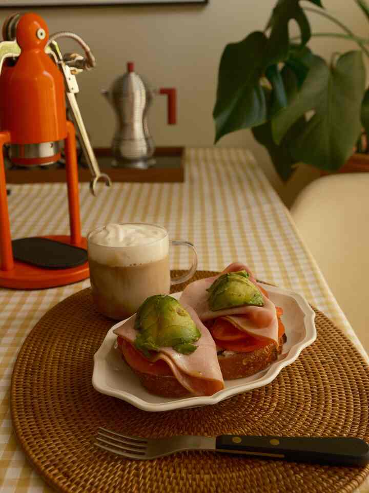 Yellow checkered tablecloth dining room table featuring avocado toast and coffee in a cozy home cafe style