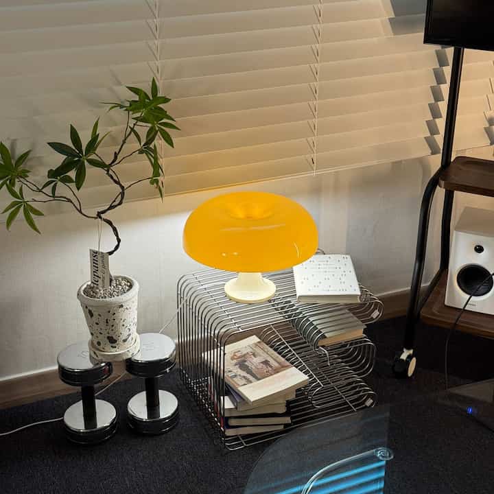 黄色のムードランプと緑のパキラの造花が置かれた暗い床のコンパクトなコーナー空間