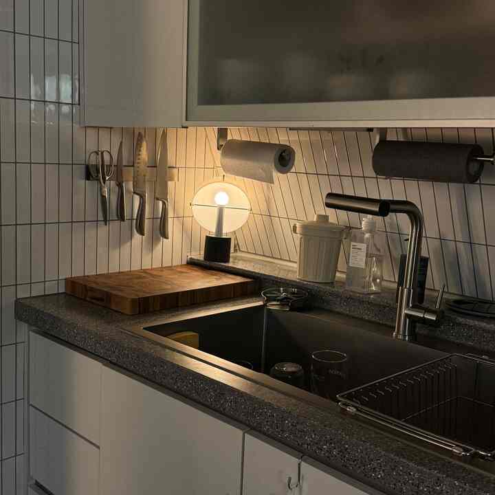 ホワイトタイルとシルバーの調理器具が配置されたモダンなキッチンシンクの空間