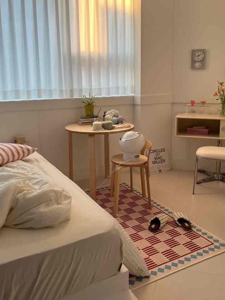 White and beige natural-tone studio bedroom featuring a bed and wooden table with cozy atmosphere