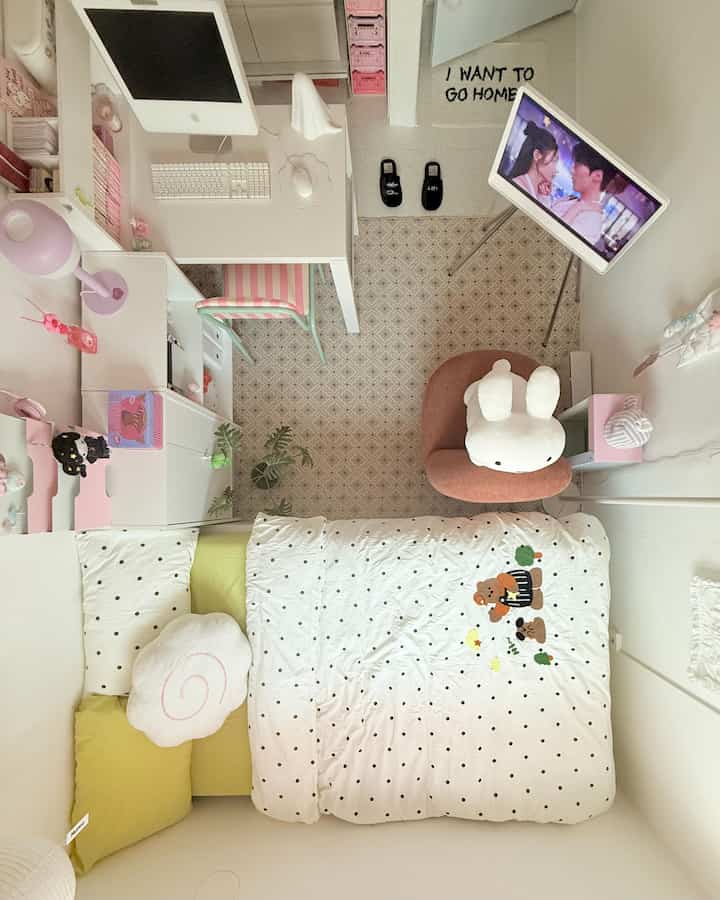 Bright white and pink toned kids' room featuring a desk, bed, and rabbit plush armchair in a cozy setup