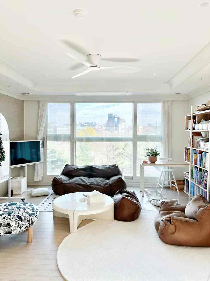 Natural toned living room in white and brown, featuring bean bag sofas, a coffee table, and bookshelf with airy atmosphere