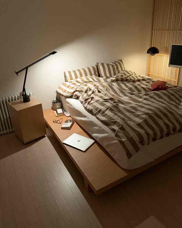 温かみのある木目調とストライプの寝具が配置されたシンプルで居心地の良い寝室