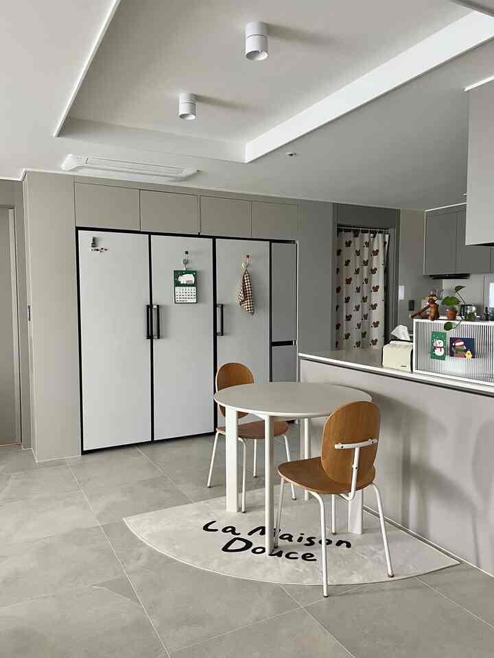 明るいグレーとナチュラルウッド調のキッチン、丸テーブルとチェアを配した雰囲気のあるインテリア