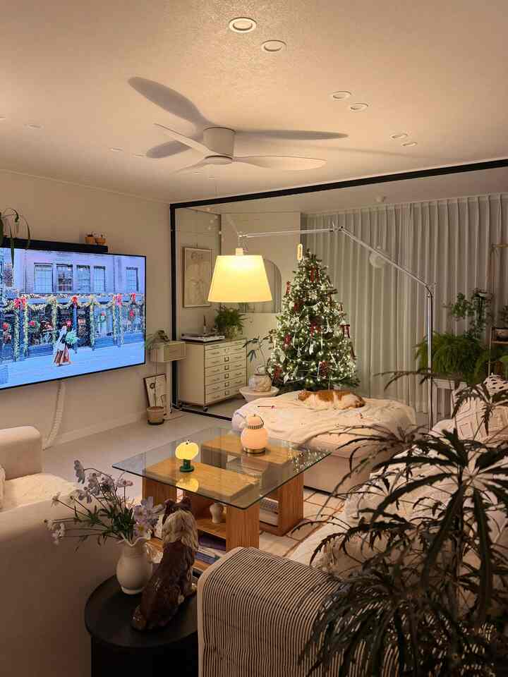 ベージュと木目調のリビング、クリスマスツリーとソファに横たわる猫がいる雰囲気のある空間