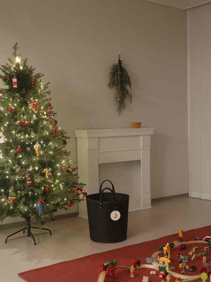 柔らかいベージュの壁と白い暖炉があるリビング、クリスマスツリーの灯りと子供のおもちゃが配置された雰囲気のある空間
