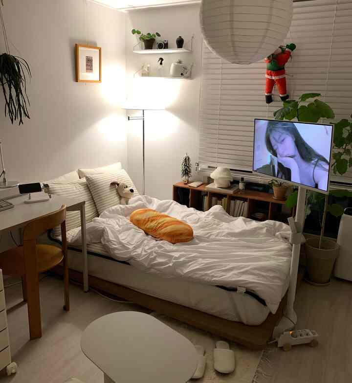 White and wood tone bedroom featuring a compact bed, TV stand, and floor lamp with a cozy atmosphere
