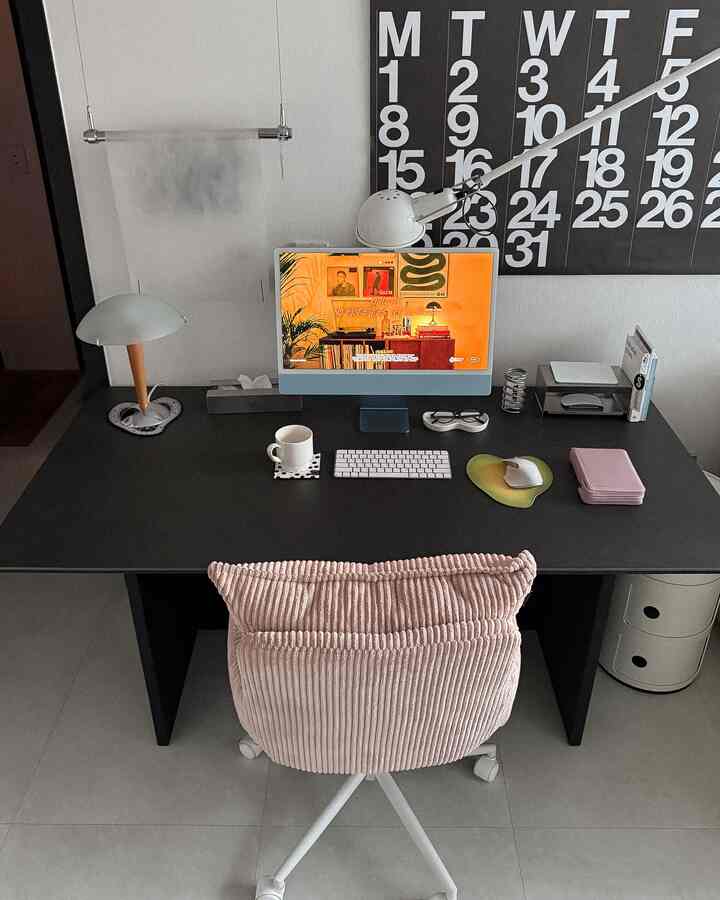 Black-toned compact home office featuring a large desk and pink office chair centrally positioned, creating a tidy remote work setup