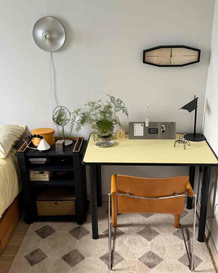 Beige-toned bedroom featuring a desk, office chair, side table, and wall clock, creating a neat and cozy home office space